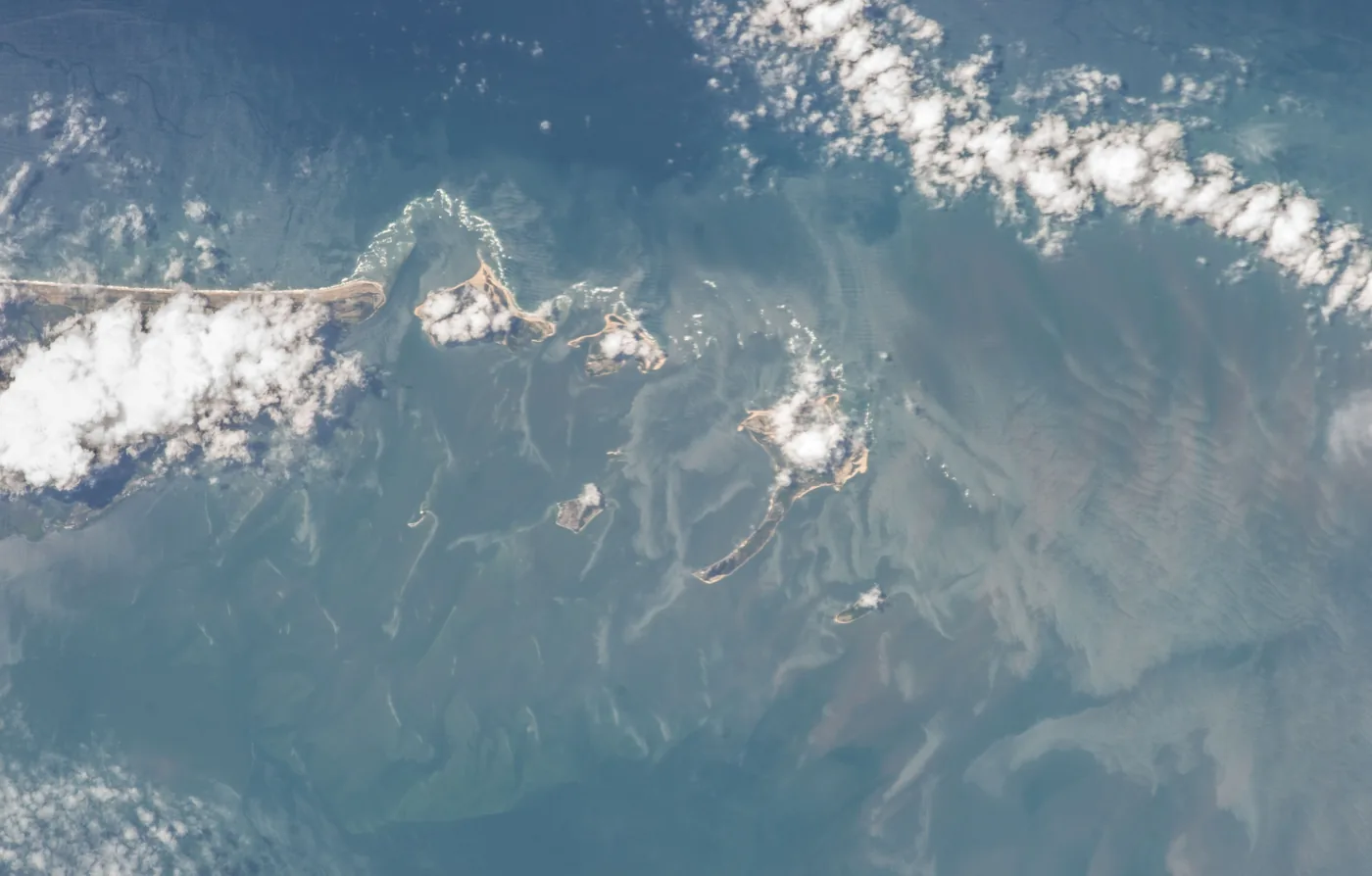 Islands and shallow coastal water off Sierra Leone under scattered clouds, photographed from the International Space Station